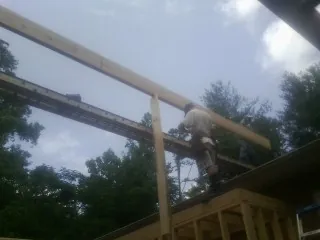 Carpenter setting a ridge beam over a new addition frame — Ice Dam Removal by Roofing Brothers in Albia