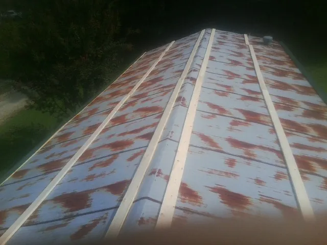 Rusted metal roof panels with new wood purlins before replacement — Storm Damage Roof Repair in Albia by Roofing Brothers
