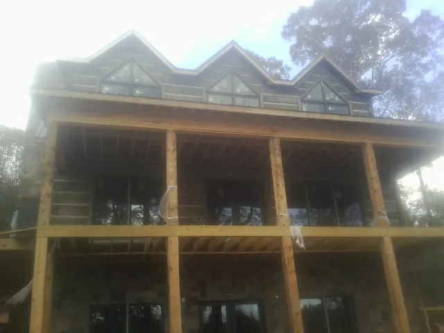 Dormers and porch framing on a large log home under construction — Roof Coating work by our crew in Albia