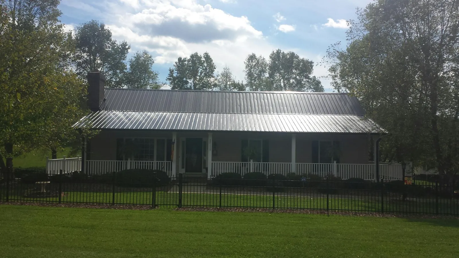 Gray metal roof on a brick ranch with a full width front porch — Gutter Guard Installation work by our crew in Albia