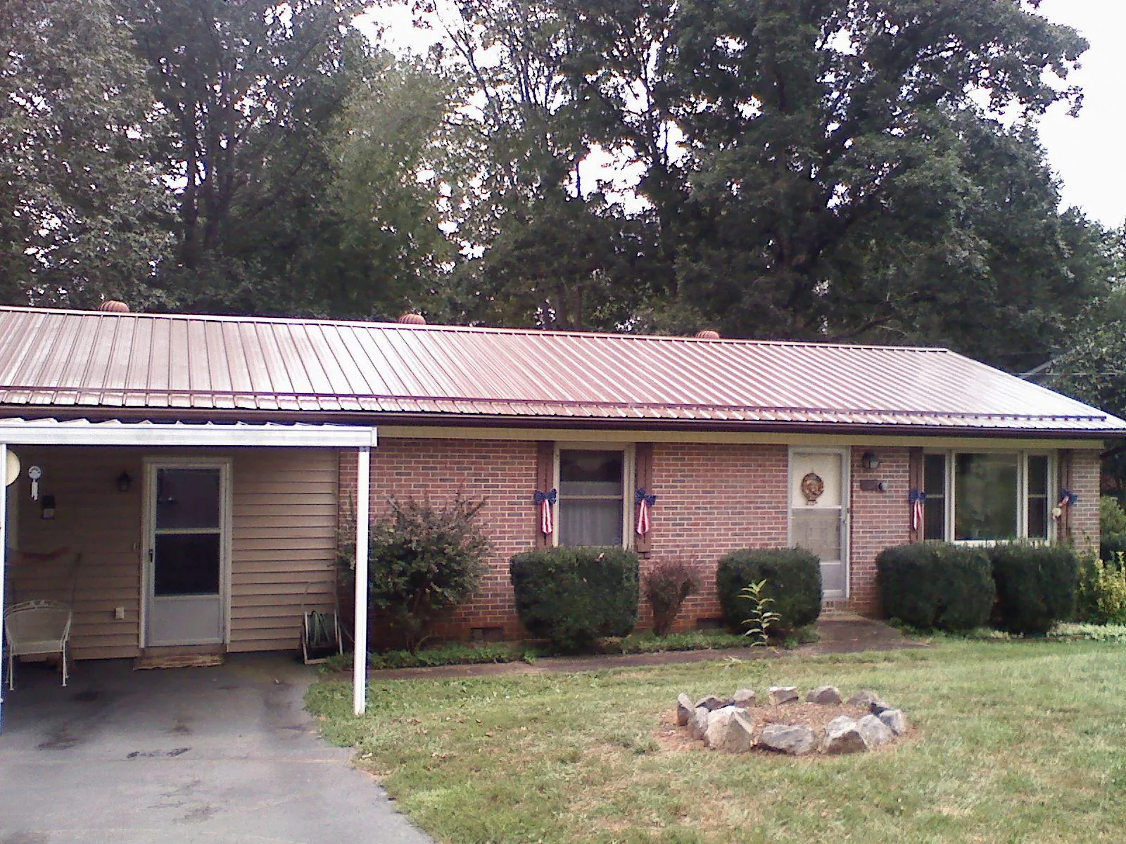 Bronze metal roof and carport on a brick ranch home — Roof Repair work by our crew in Albia