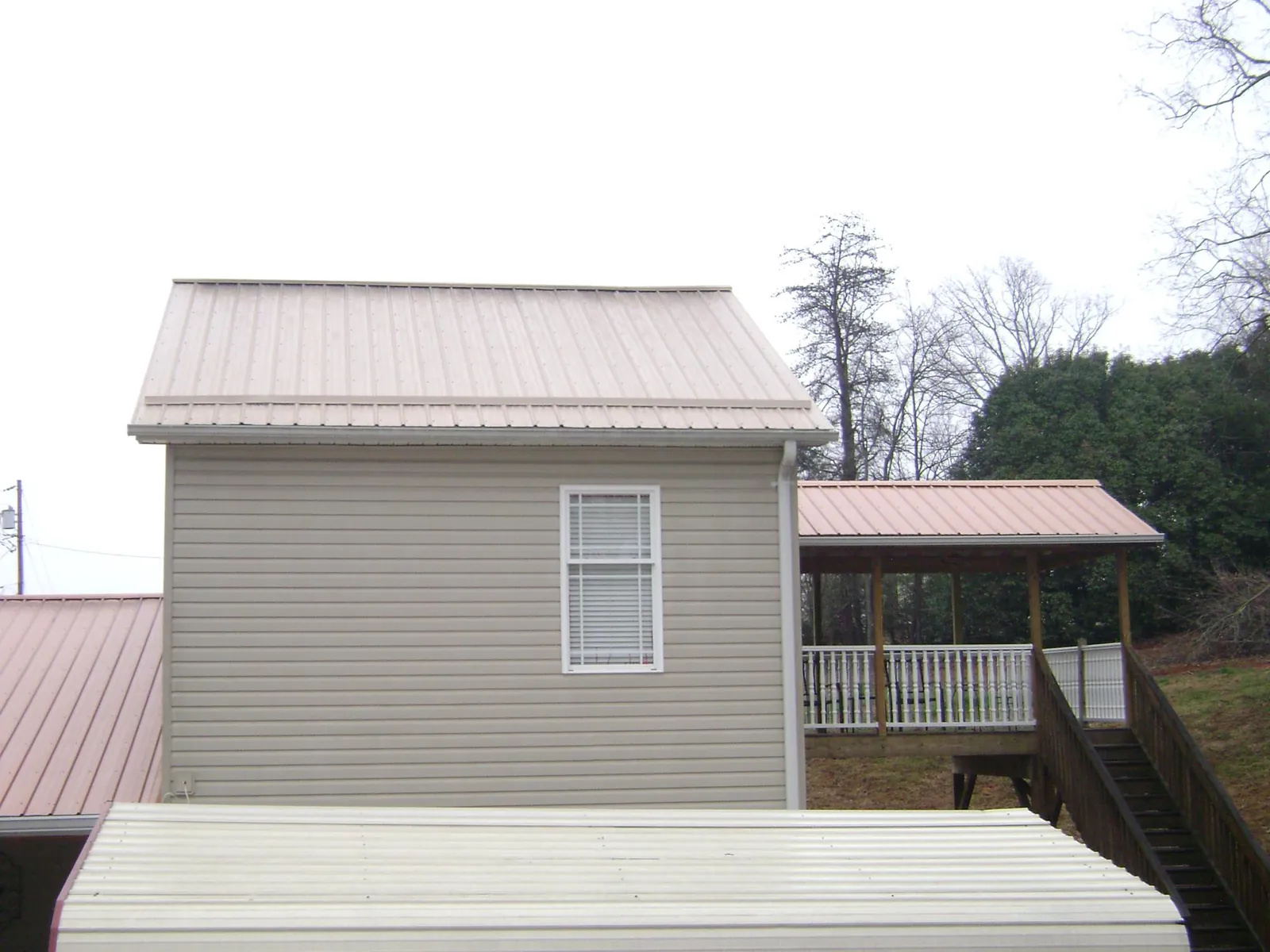 Tan metal roofs on a two story addition and attached porch, from a Roof Replacement job in Albia