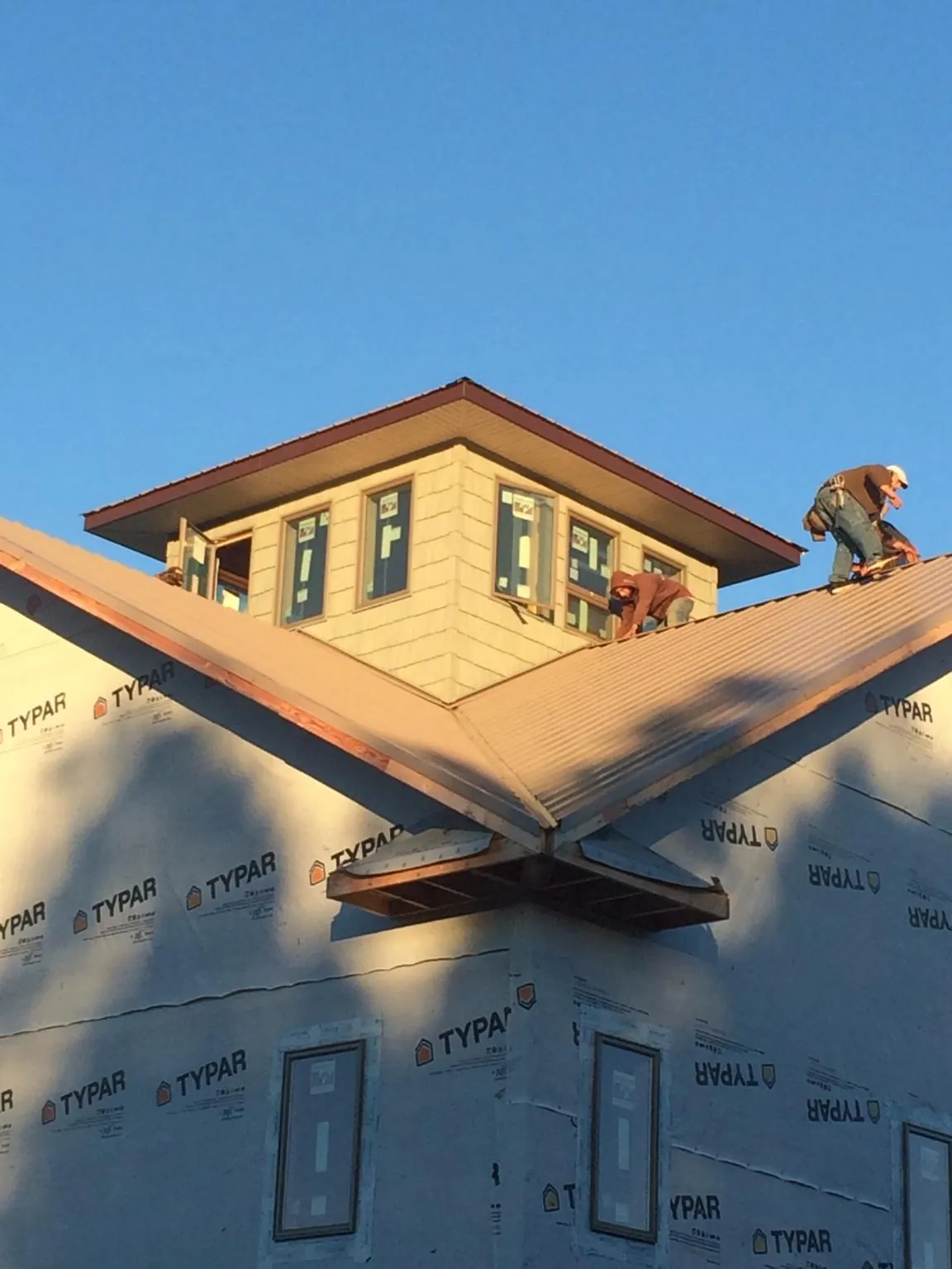 Roofers working around a rooftop cupola on a new metal roof at sunset — Roof Waterproofing in Albia by Roofing Brothers